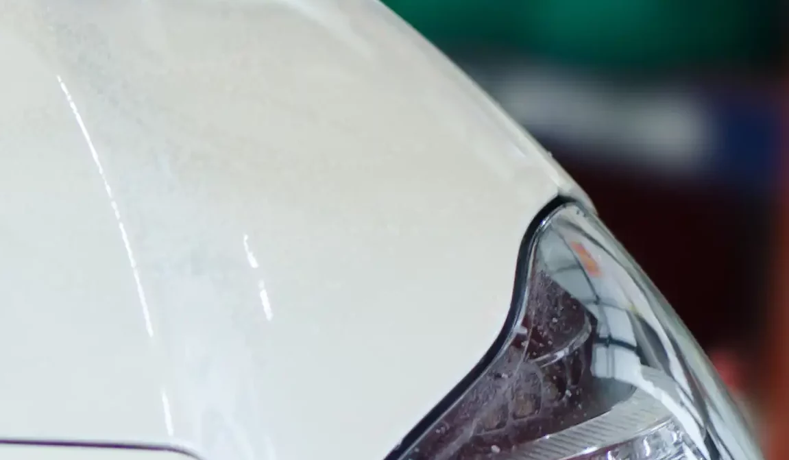 Closeup of a stone chip damage on a white car after repair.