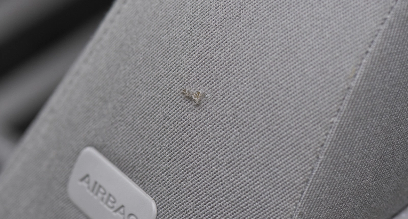 Before image of tear in a car seat with grey fabric.