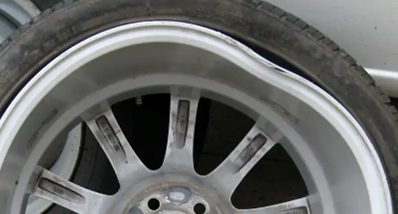 Closeup of a misaligned alloy wheel before a repair.