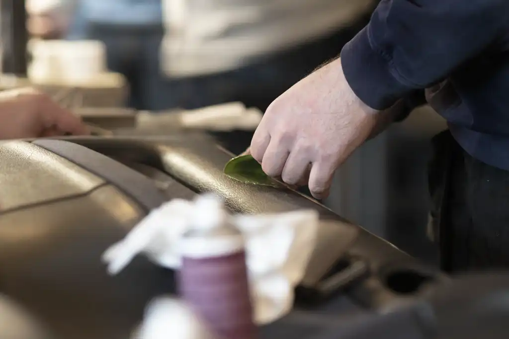 Ein Techniker repariert ein kleines Loch im Armaturenbrett eines Autos.