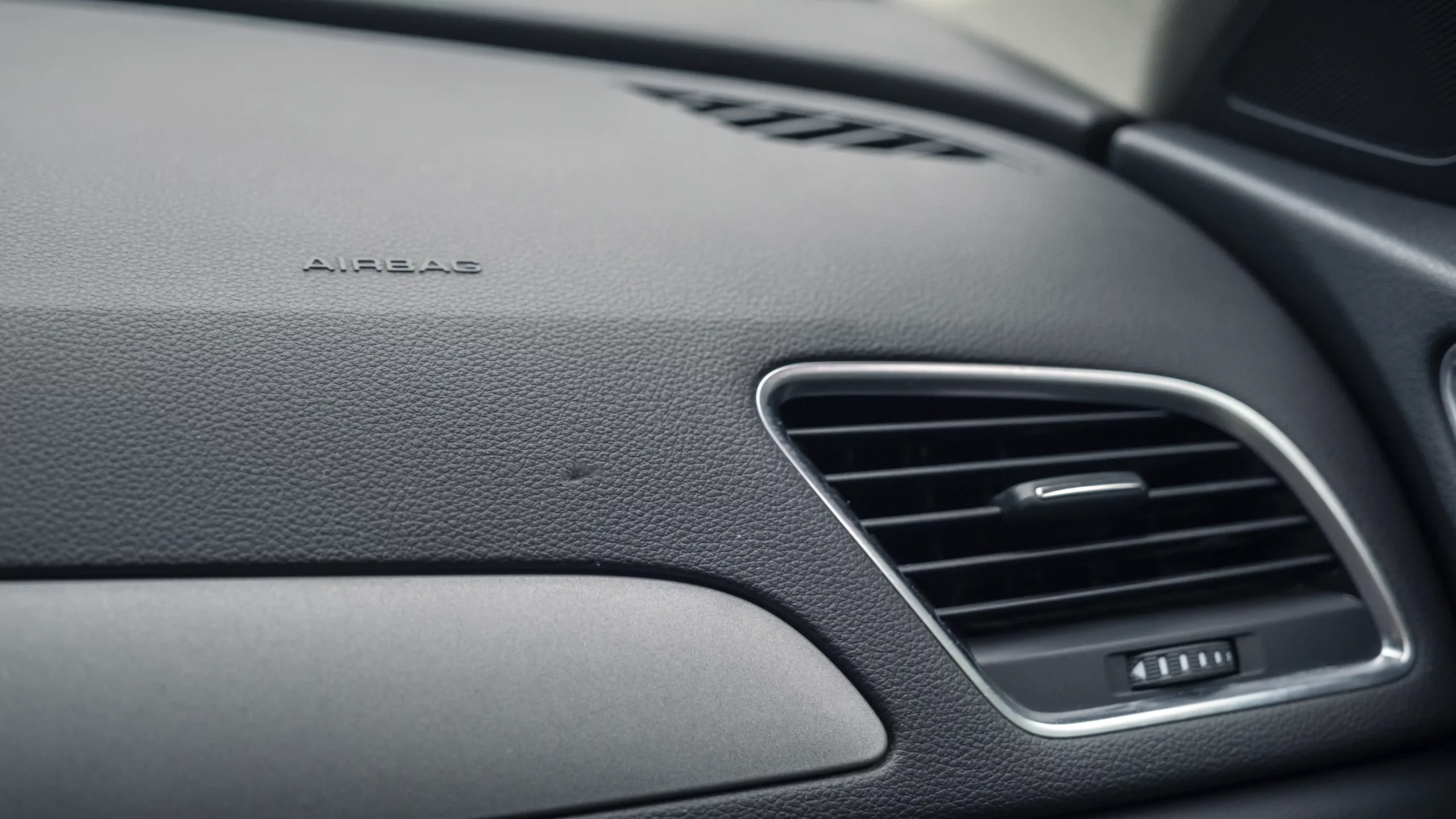 Closeup of a cosmetic damage on a car dashboard before repair.