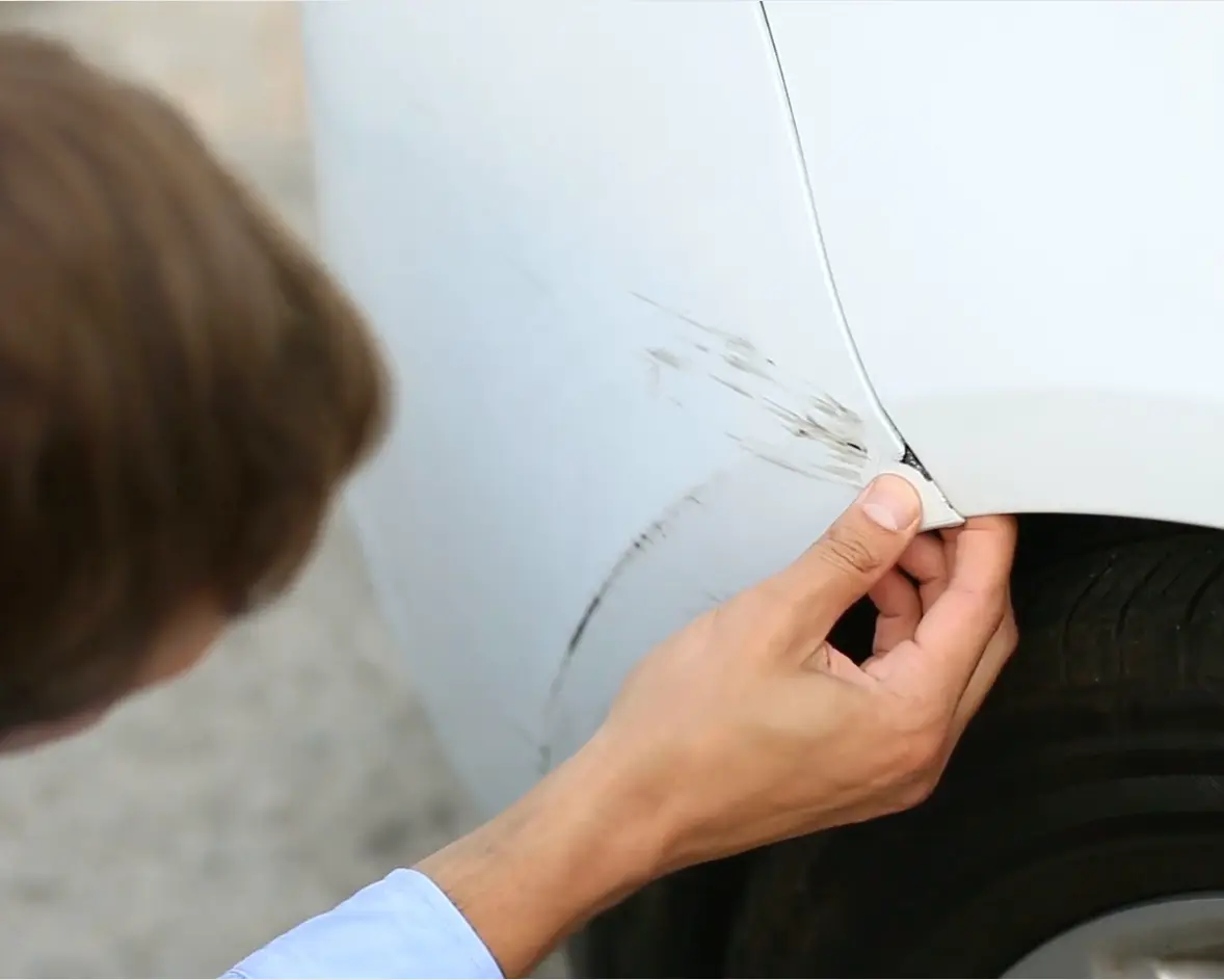 En man tittar på en repa på sin bil