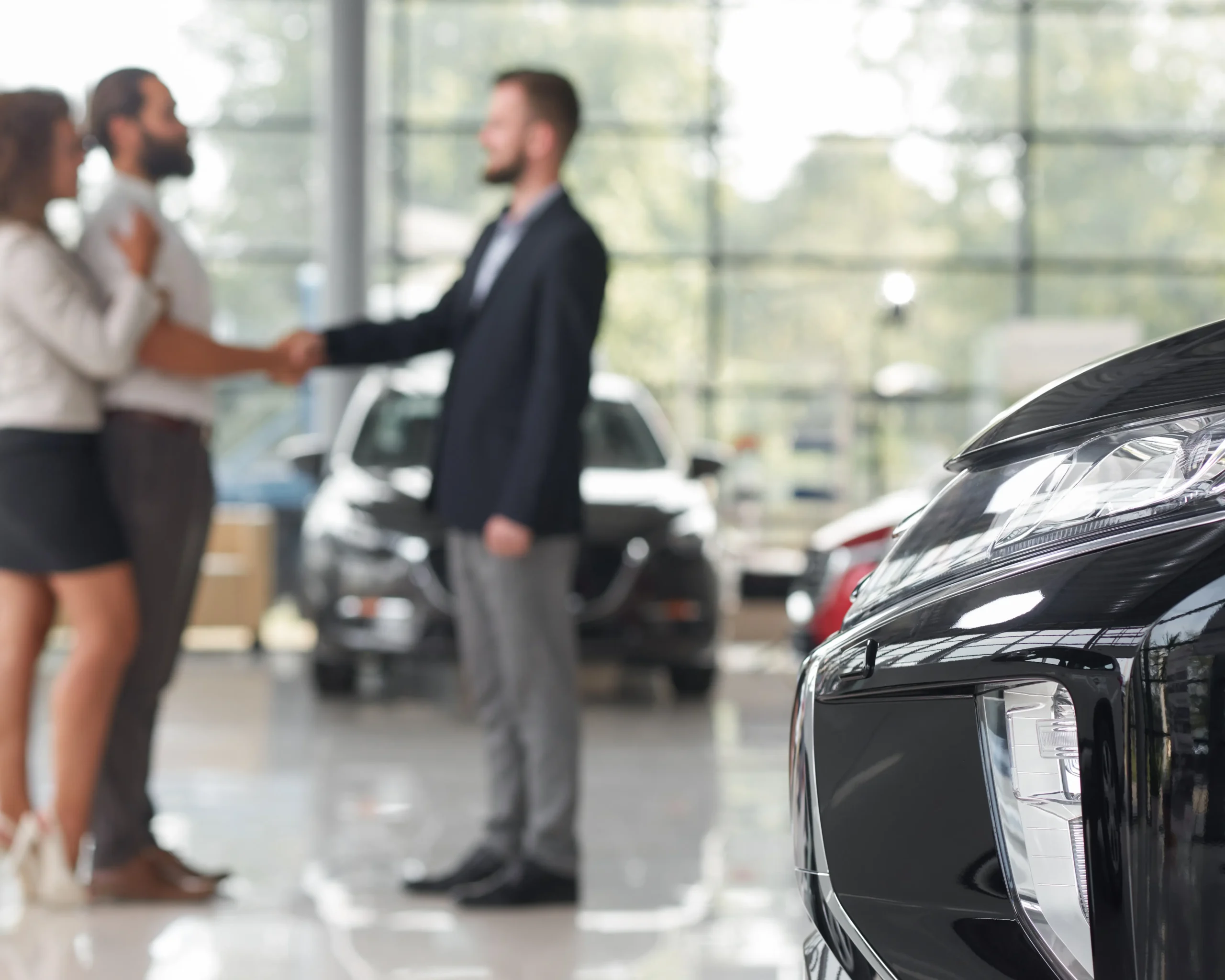 Ett par skakar hand med en man i ett showroom för biluthyrning