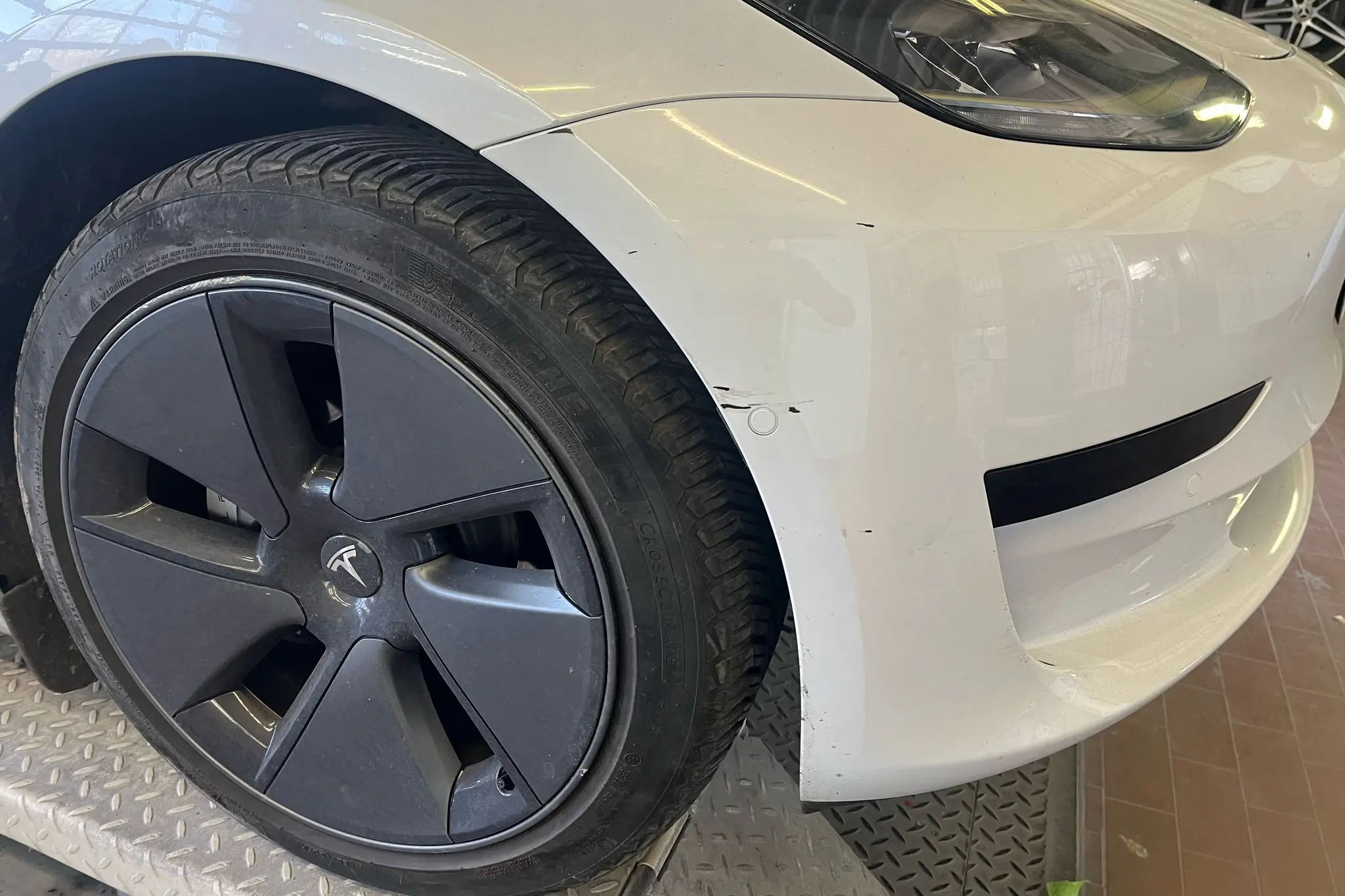 لقطة مقربة لمقدمة سيارة تيسلا بيضاء مع تلف في الطلاء