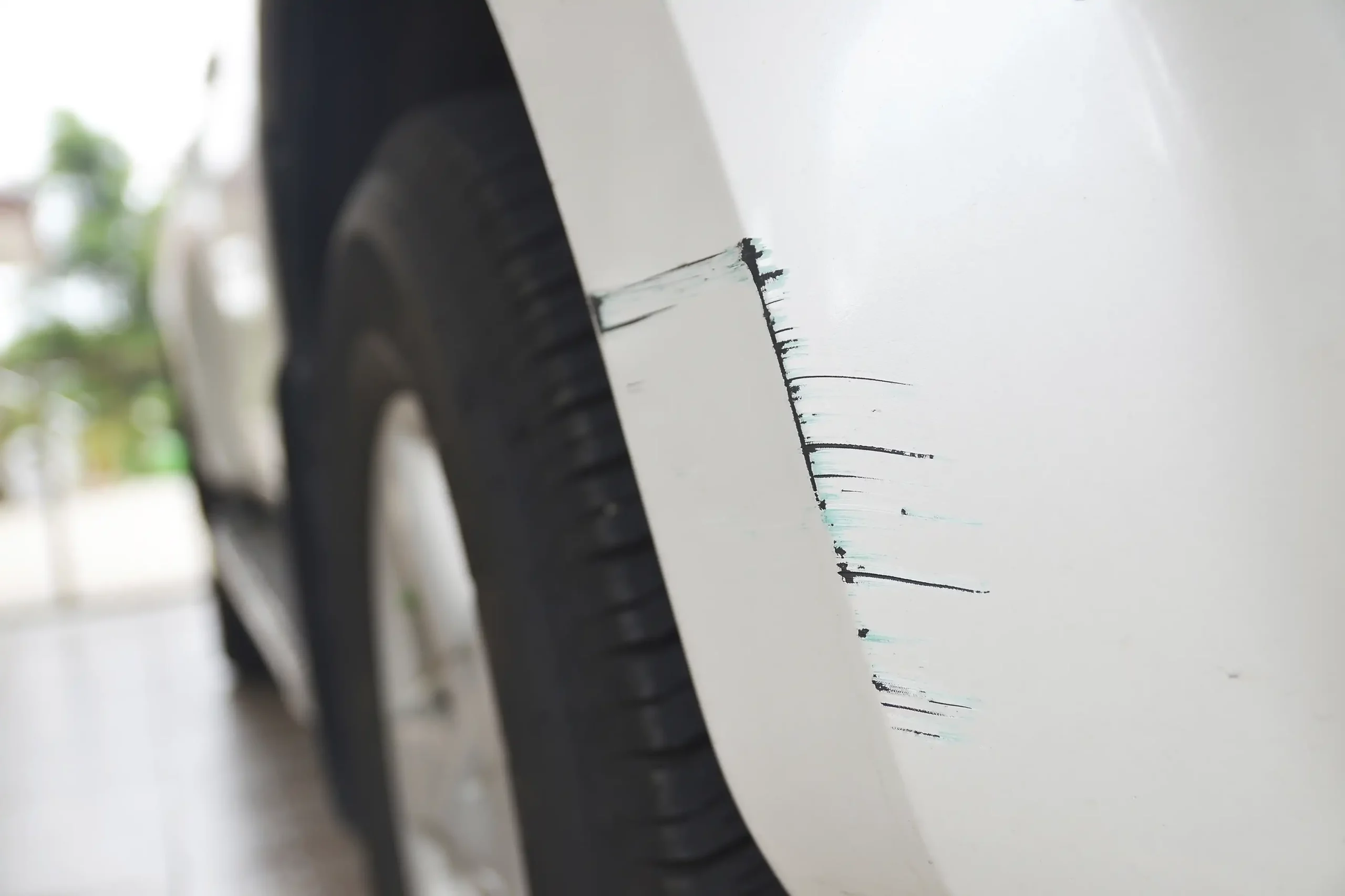 Closeup of a paint scratch on a white car.