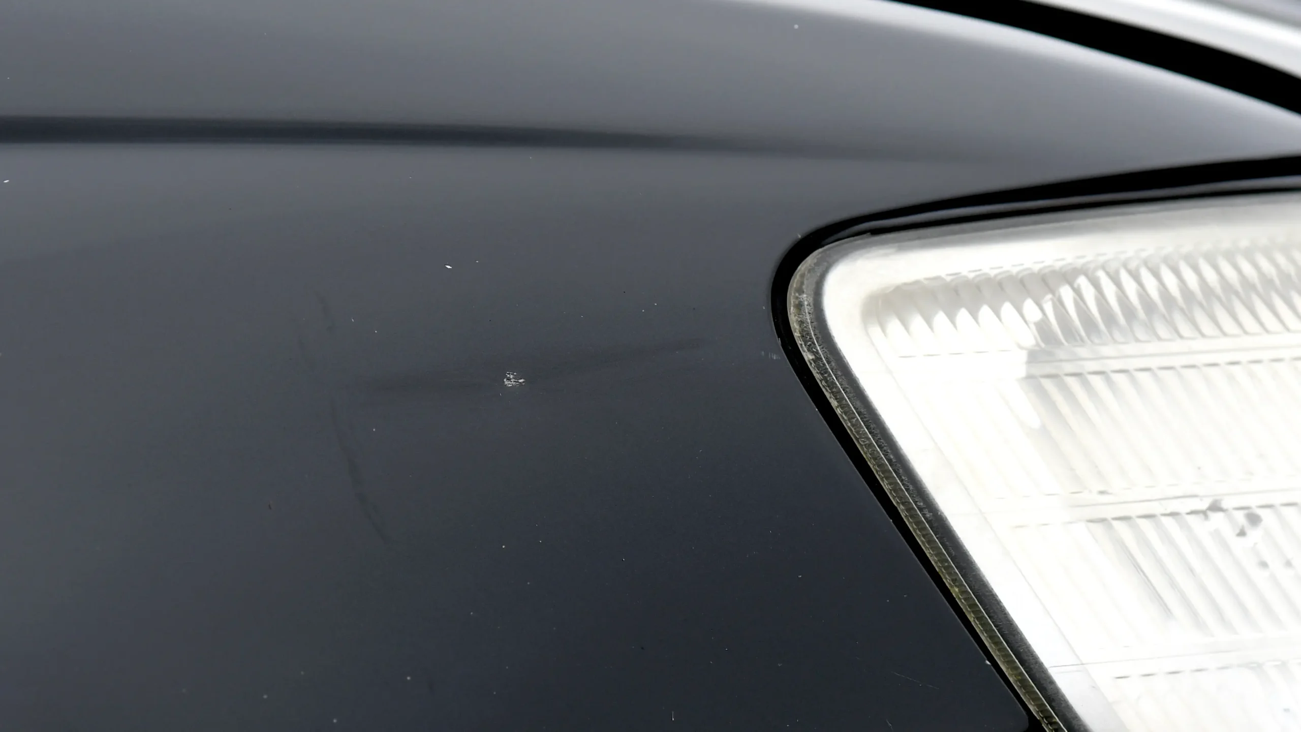 Paint stone chip on a black car close to the front headlight