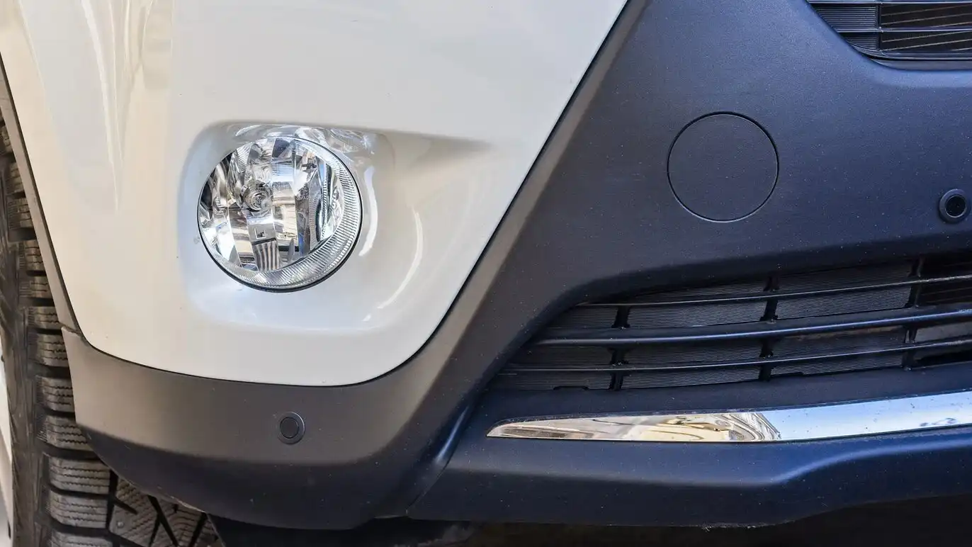 A plastic bumper in front of white car.