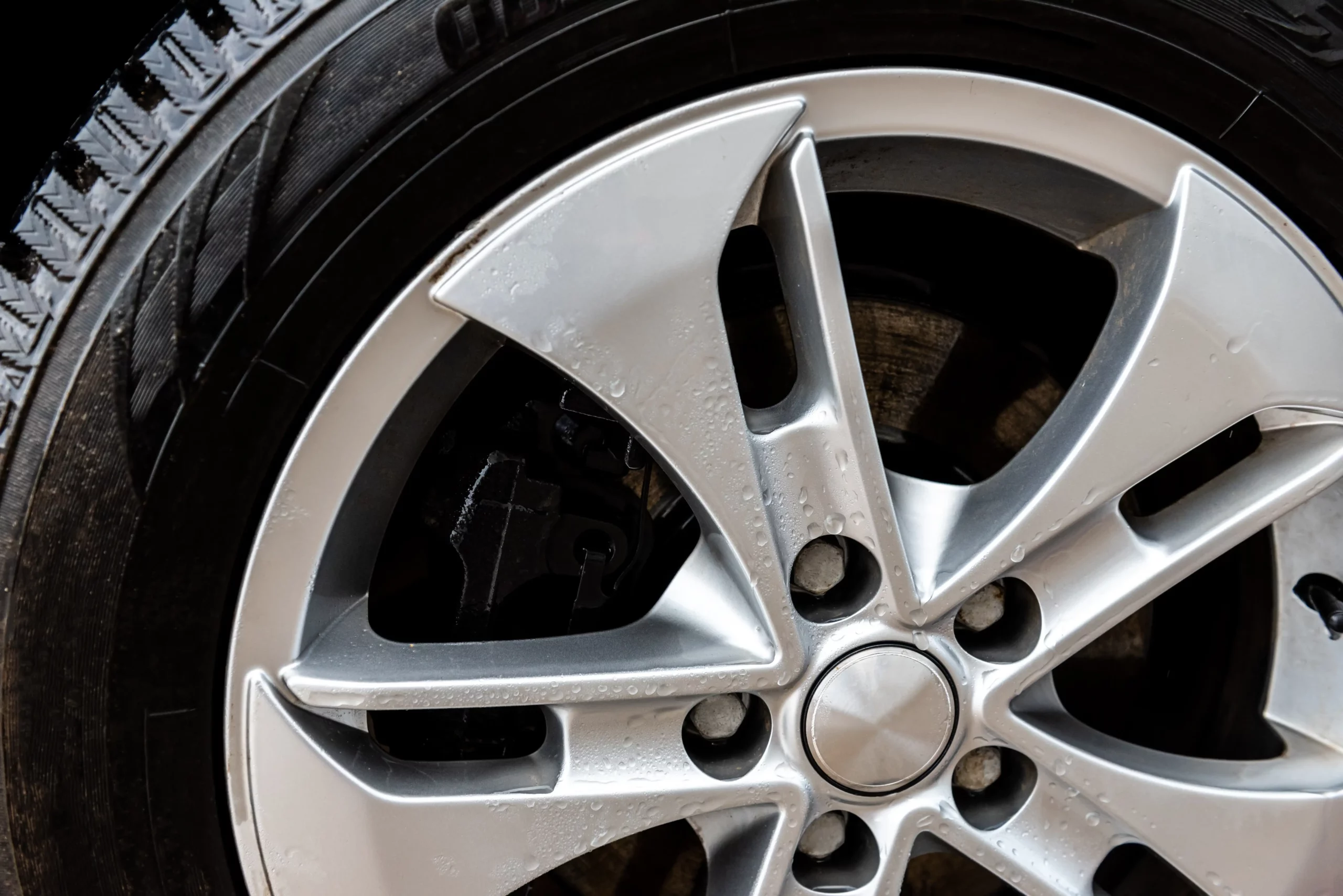Silver colored alloy wheel with curb damage.