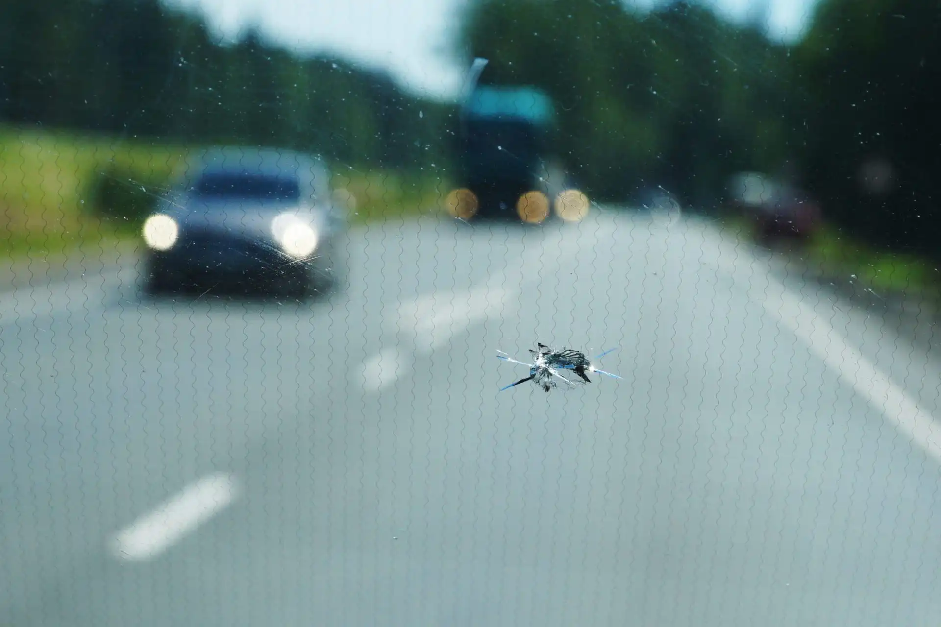 ein Steinschlagschaden an der Windschutzscheibe aus dem Inneren eines Autos betrachtet.