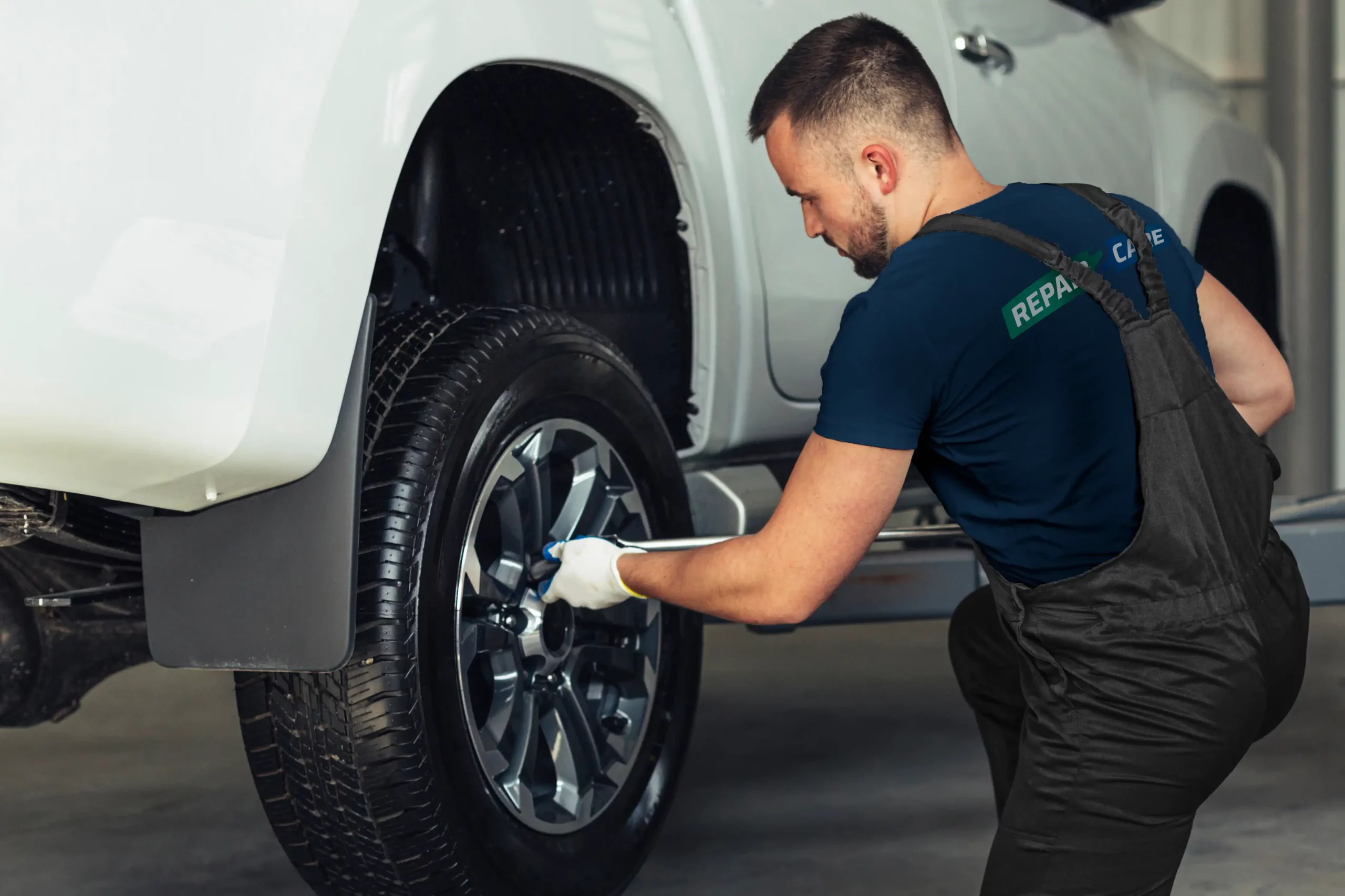 Tekniker avlägsnar däck från bilen före fälgreparation.