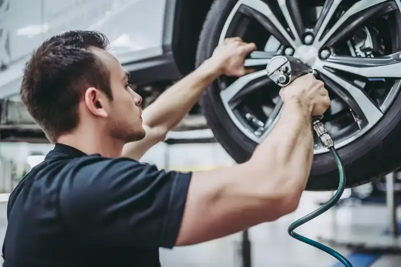 Technician installing tire on a car in Repair2Care shop.