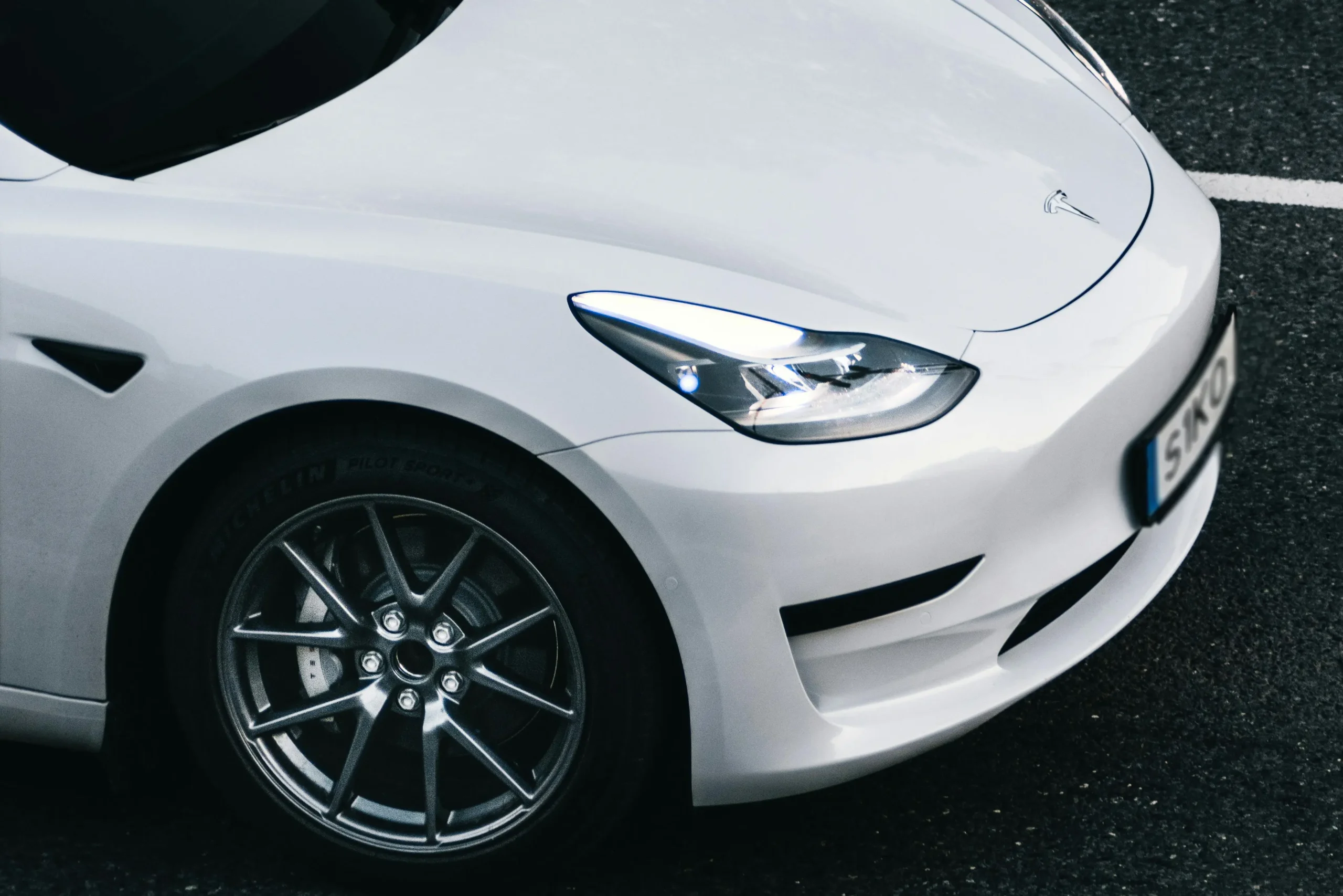 لقطة مقرّبة للواجهة الأمامية لسيارة تسلا بيضاء اللون