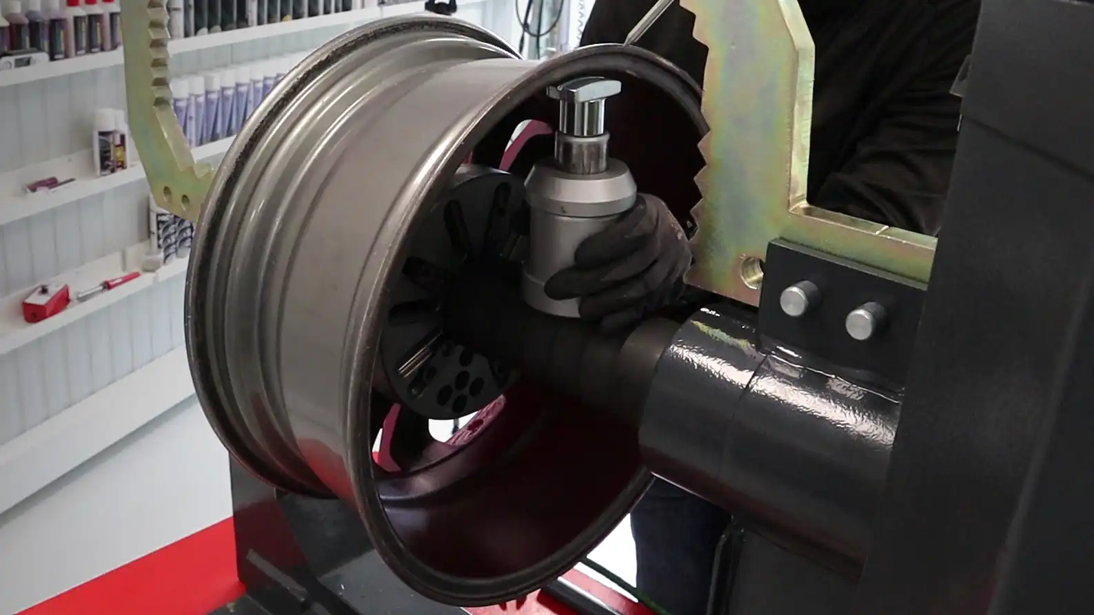 a bent alloy wheel being restored in a wheel straightening machine.