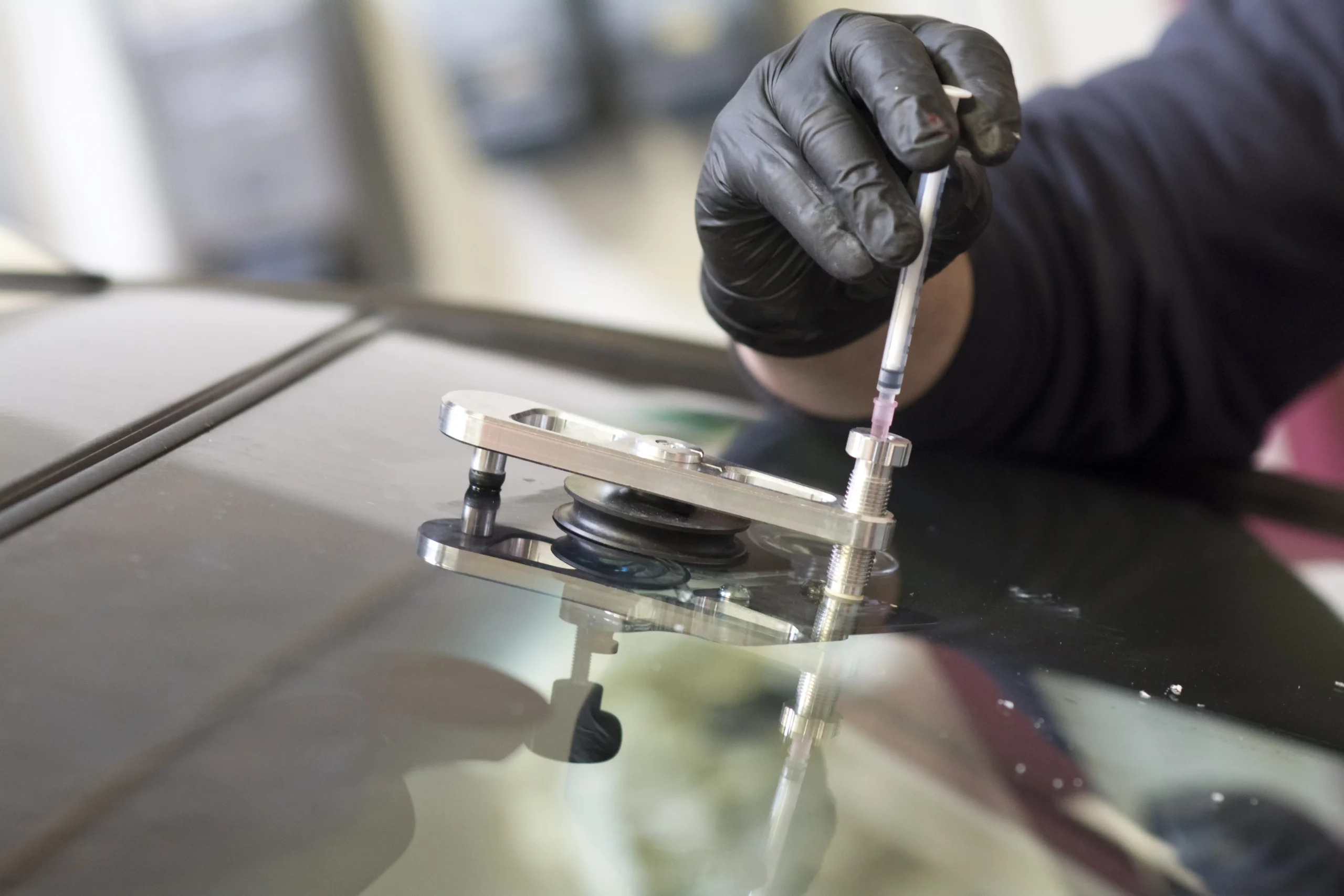 A technician performing a windshield repair and filling the crack in the windshield with resin.