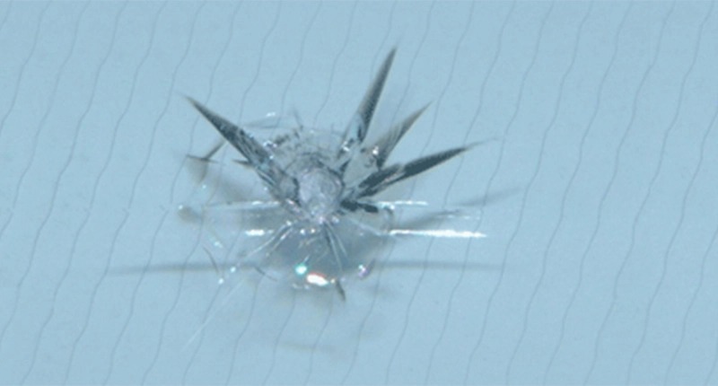 Closeup of a stone chip damage on a windscreen before repair.