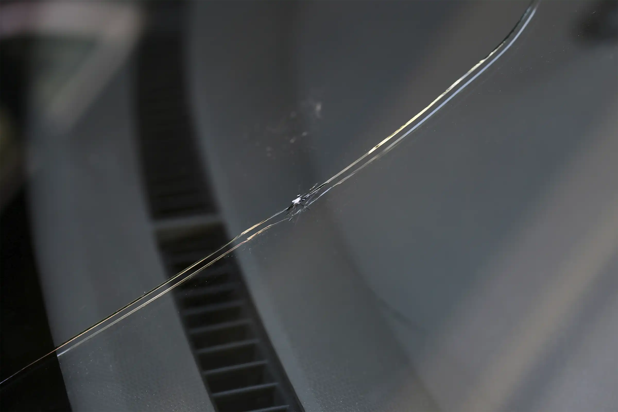 Closeup of a crack in the windshield of a car.