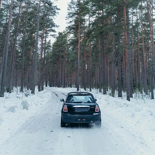 Black car driving on road with snow on it