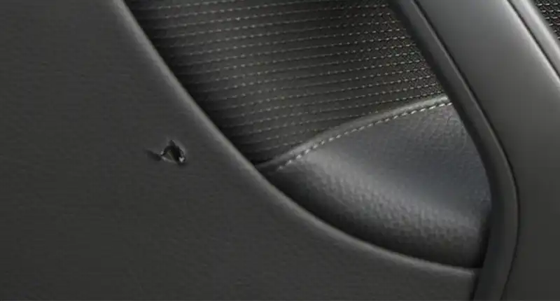 Hole in black leather car interior.