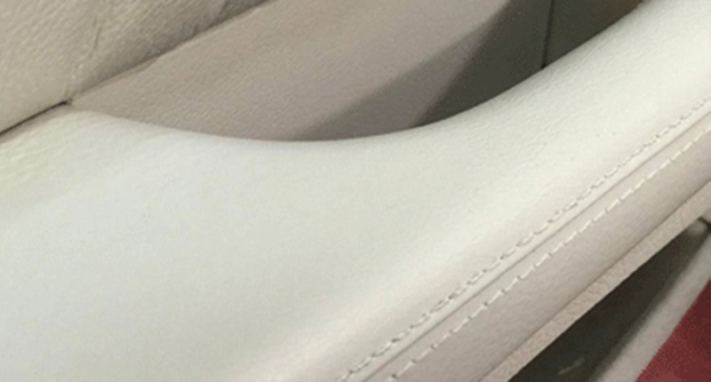 Restored car armrest in white leather with a smooth and even colored surface.